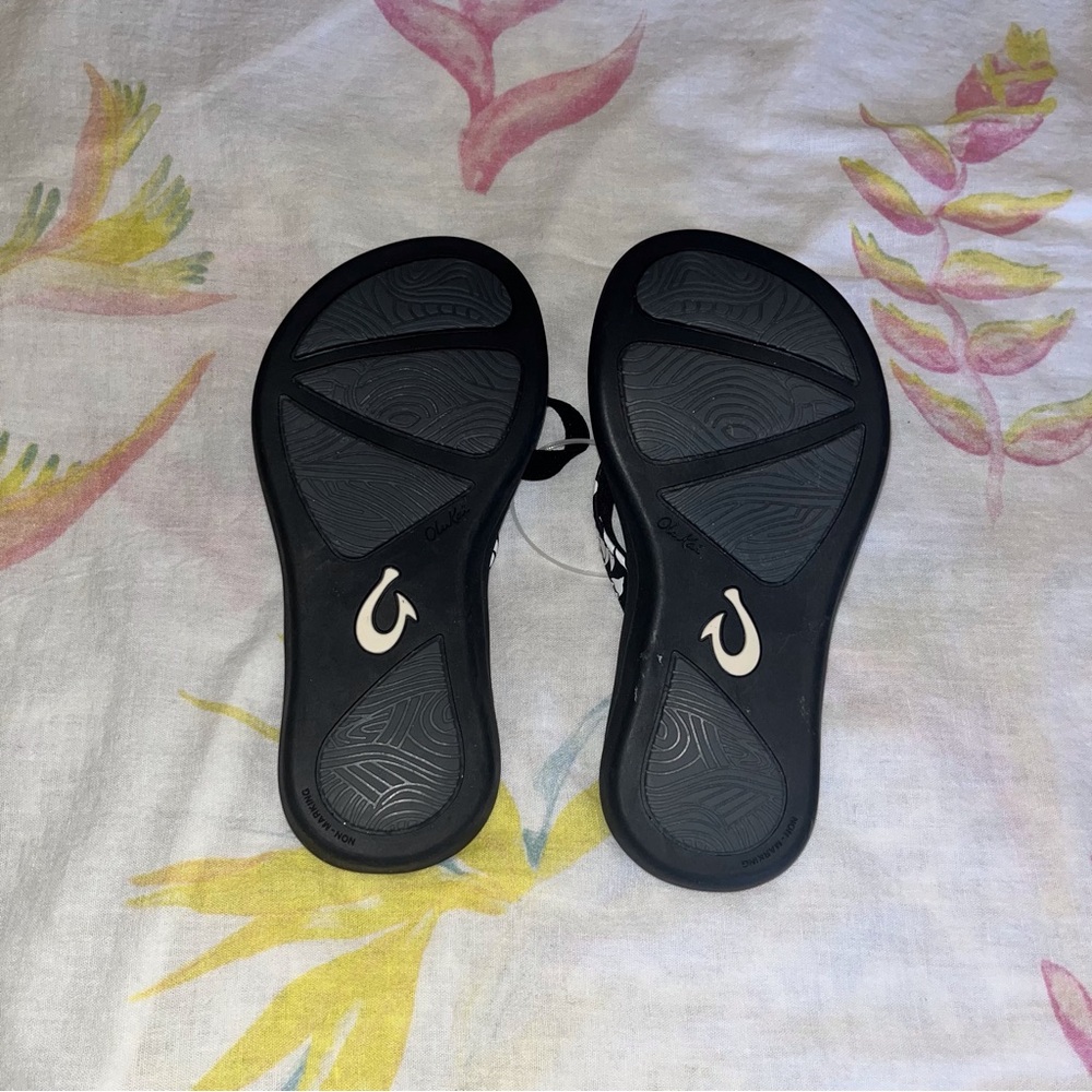 Child’s OluKai Black Sandals with White Hawaiian Flowers trim Size 11